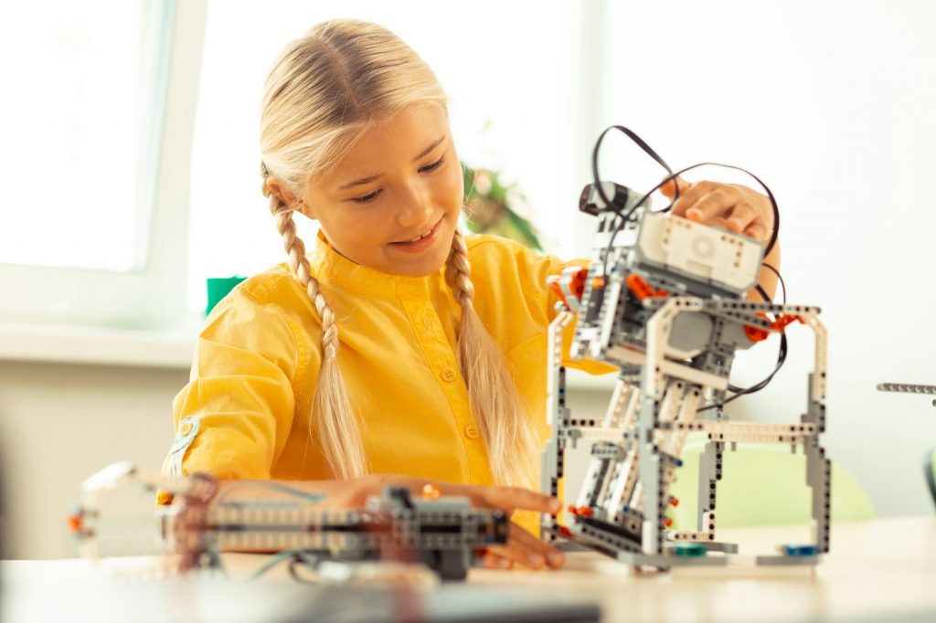 Girl playing with a robot at science lesson